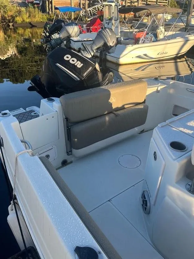 Slide: The Image of 2023 Crownline 220 CC Finseeker boat interior with seating and motor, docked by the water. - 7