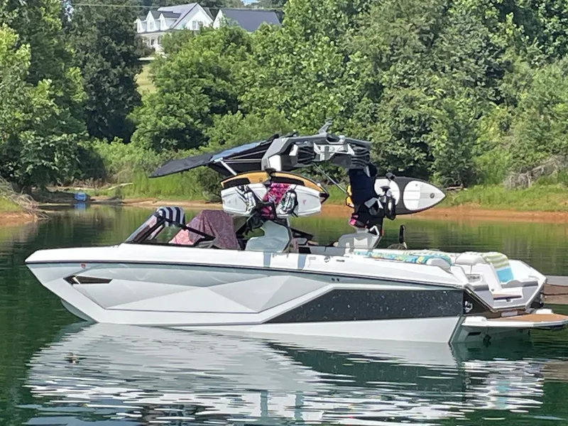 Slide: The Image of 2023 Nautique Super Air G23 boat on a serene lake with lush greenery. - 54