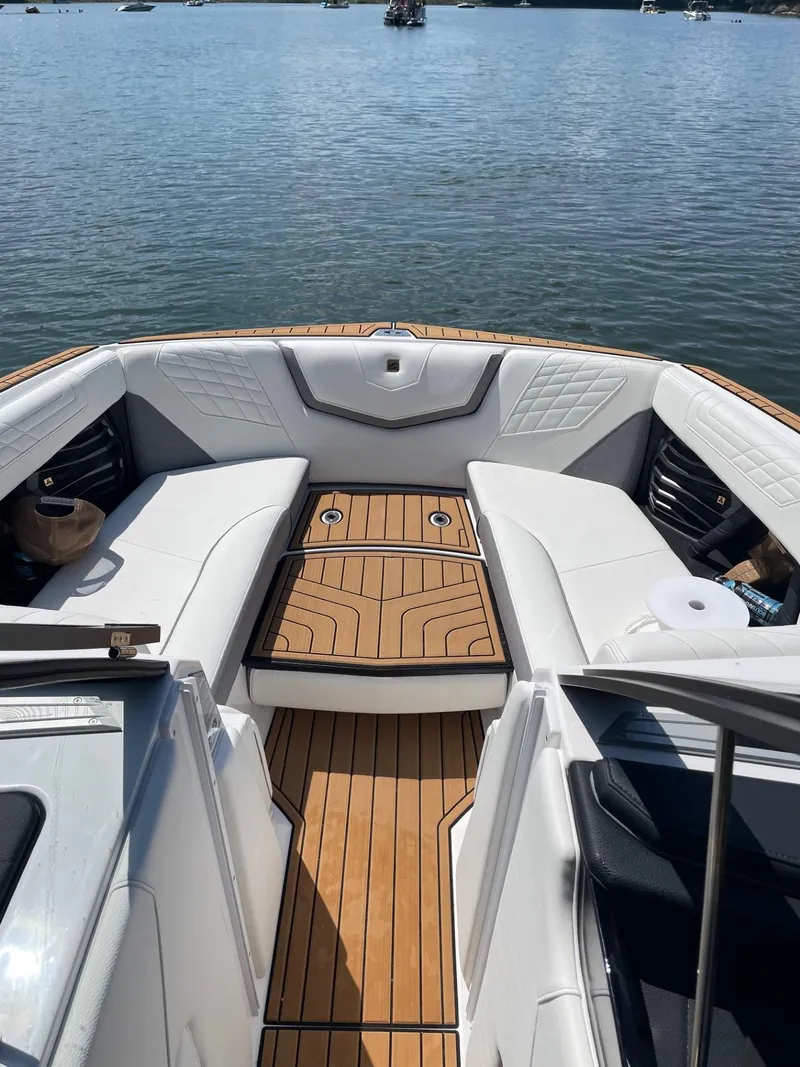 Slide: The Image of 2023 Nautique Super Air G23 boat interior with teak flooring on a sunny lake. - 58