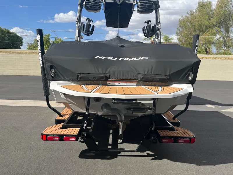 Slide: The Image of 2023 Nautique Super Air G23 boat with cover, rear view, parked outdoors. - 60