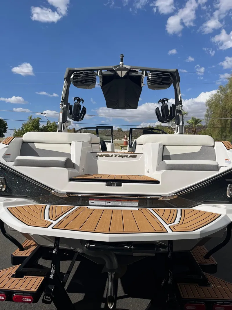 Slide: The Image of 2023 Nautique Super Air G23 boat with teak deck, rear view under blue sky. - 62