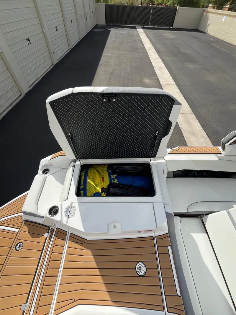 Slide: The Image of 2023 Nautique Super Air G23 boat with open storage compartment, teak deck, and modern design. - 73