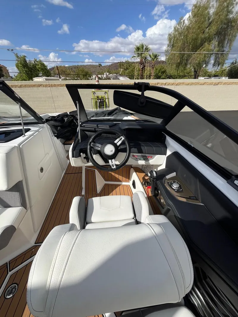 Slide: The Image of 2023 Nautique Super Air G23 boat interior with steering wheel and seating, under a clear blue sky. - 86