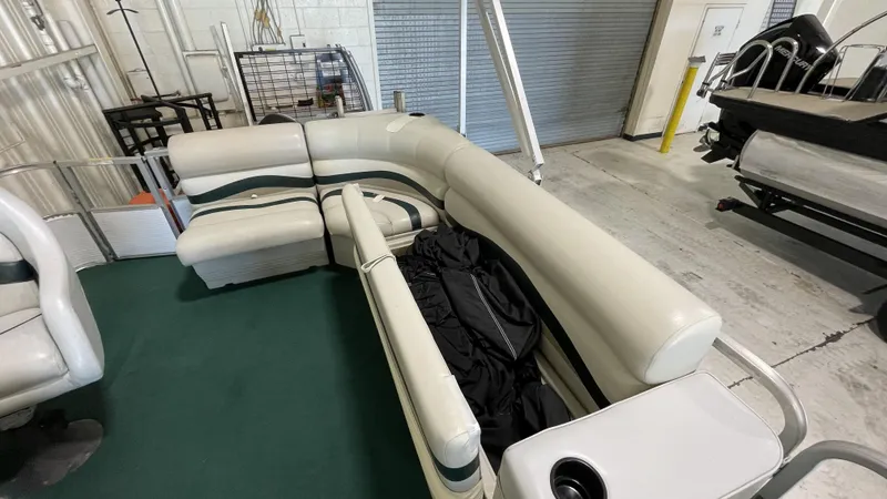 Slide: The Image of Sweetwater 2350 pontoon boat interior with white seating, green carpet, and storage area, 1991 model. - 10
