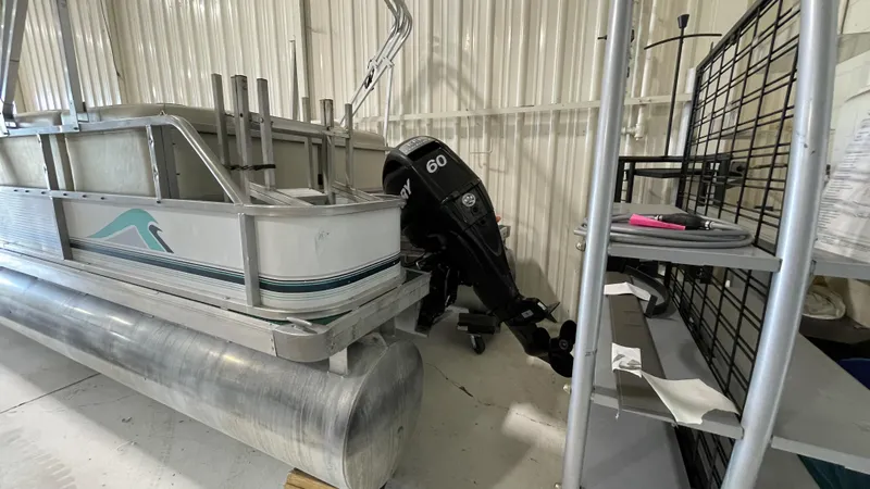 Slide: The Image of Sweetwater 2350 pontoon boat from 1991 with a 60 HP outboard motor in storage. - 6
