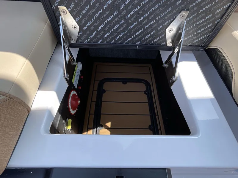 Slide: The Image of 2025 Nautique Super Air S S23 storage compartment with open hatch and control panel. - 11