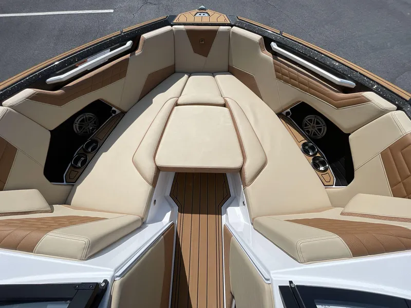 Slide: The Image of 2025 Nautique Super Air S S23 boat interior with tan and brown seating, cup holders, and speakers. - 30