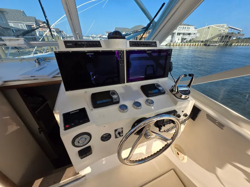 Slide: The Image of 2007 Carolina Classic 35 boat helm with dual screens and steering wheel, dockside view. - 3