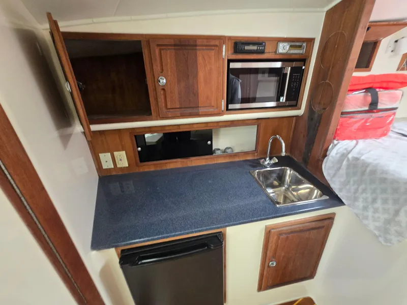 Slide: The Image of Compact kitchen area in a 2007 Carolina Classic 35 boat with sink, microwave, and fridge. - 30