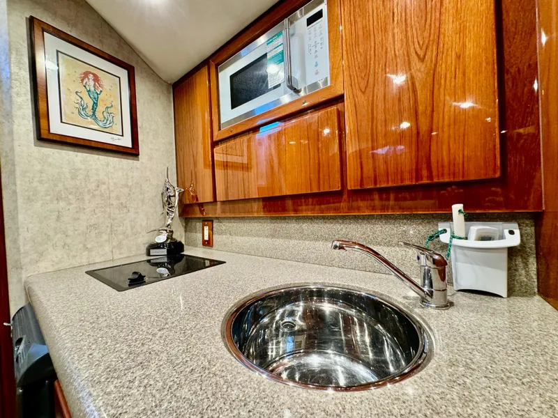 Slide: The Image of 2004 Predator 35 yacht kitchen with sink, microwave, and wooden cabinets. - 24