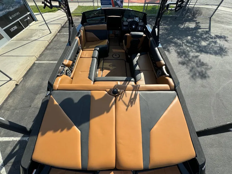 Slide: The Image of 2021 Axis A22 boat interior with tan and black seating, parked outdoors. - 10