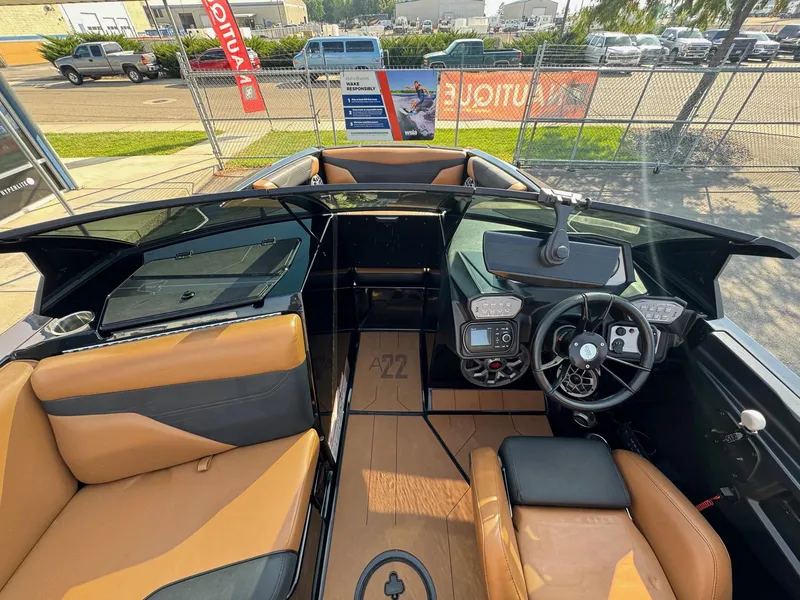 Slide: The Image of 2021 Axis A22 boat interior with tan and black seating, modern dashboard, and steering wheel. - 12