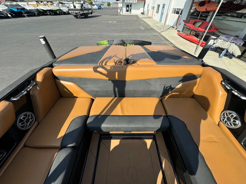 Slide: The Image of 2021 Axis A22 boat interior with tan and black seating, parked near a service center. - 14