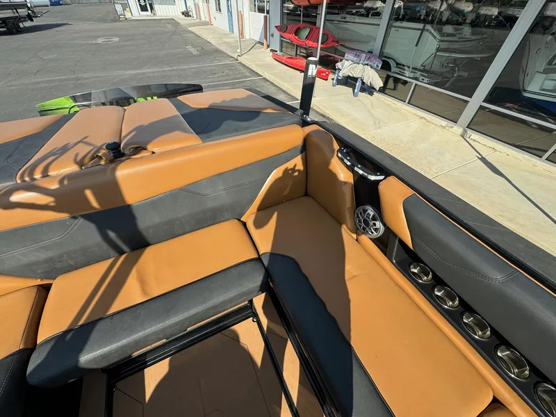 Slide: The Image of 2021 Axis A22 boat interior with tan and black seating, docked near a building. - 15