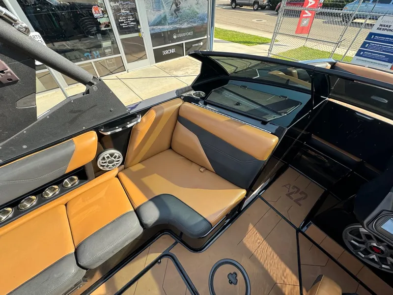 Slide: The Image of 2021 Axis A22 boat interior with tan and gray seating, cup holders, and speaker system. - 18