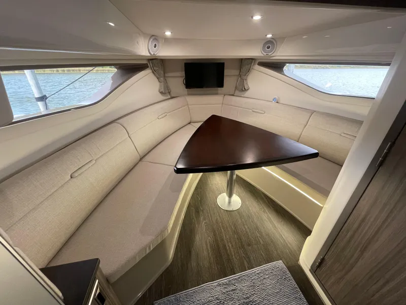 Slide: The Image of 2020 Sea Ray Sundancer 320 cabin interior with triangular table and beige seating. - 29