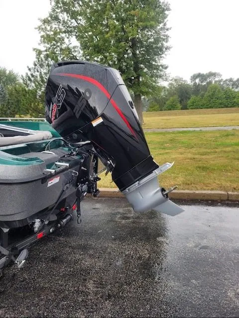 Slide: The Image of 2024 Ranger 2080MS boat with powerful outboard motor, parked on wet pavement. - 2