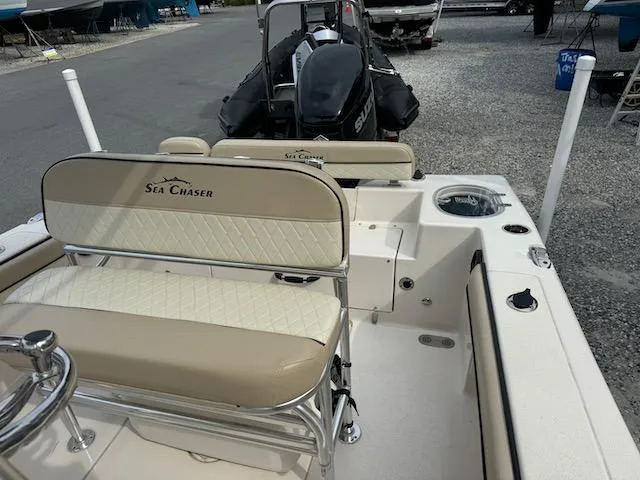 Slide: The Image of 2022 Sea Chaser 22 HFC boat interior with seating and motor, parked on gravel. - 16