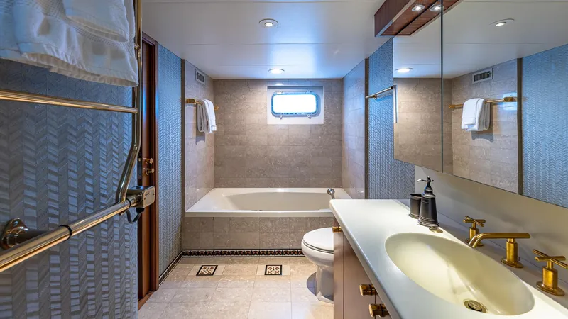 Slide: The Image of Luxurious yacht bathroom with bathtub, gold fixtures, and elegant design, Feadship Custom 1985 model. - 11