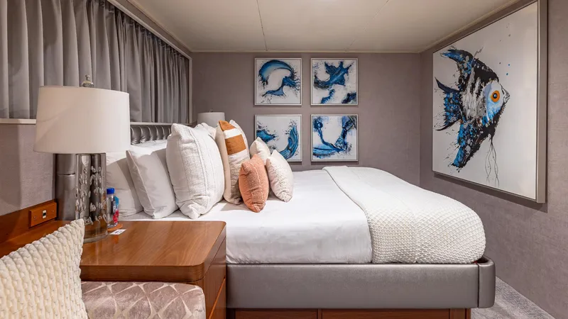 Slide: The Image of Luxurious yacht bedroom with modern decor, featuring marine-themed artwork and plush bedding. - 16