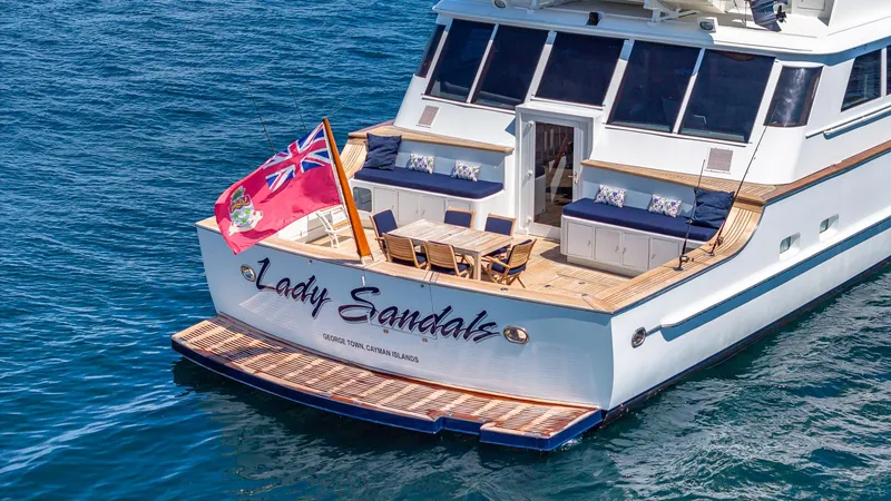 Slide: The Image of Feadship Custom 1985 yacht "Lady Sandals" with deck seating and flag on open water. - 21