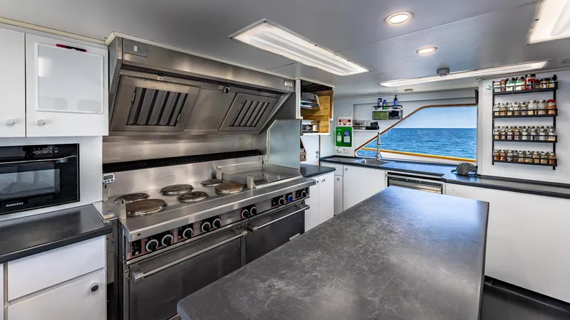 Slide: The Image of Modern yacht kitchen with stainless steel appliances, ocean view, and ample counter space. Feadship Custom 1985. - 29