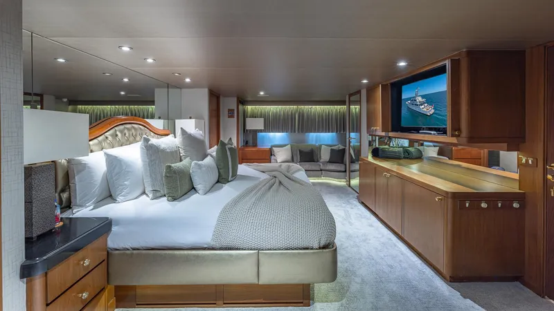 Slide: The Image of Luxurious yacht bedroom with elegant decor, featuring a large bed, TV, and seating area. Feadship Custom 1985. - 9