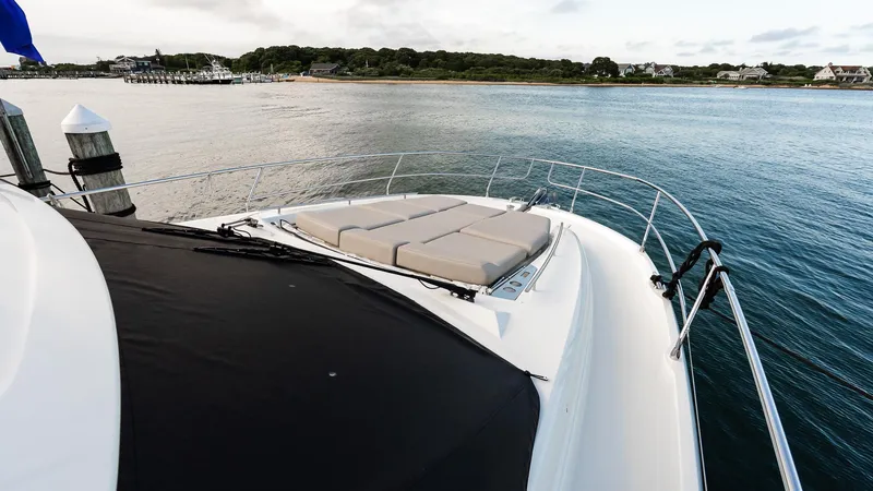 Slide: The Image of 2019 Prestige 520 Flybridge yacht docked by serene waters, featuring spacious sunbathing area. - 26