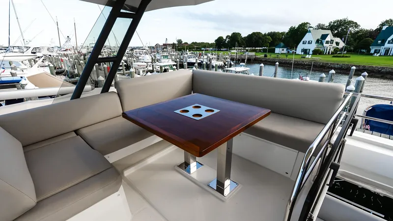 Slide: The Image of Flybridge seating area on 2019 Prestige 520 yacht, featuring a wooden table and marina view. - 31