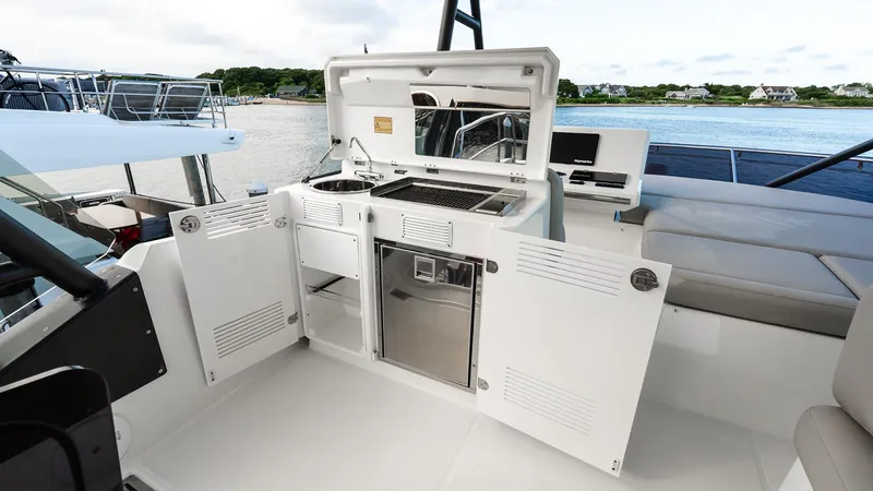 Slide: The Image of Flybridge kitchen on 2019 Prestige 520 yacht with grill and seating, overlooking serene waters. - 33