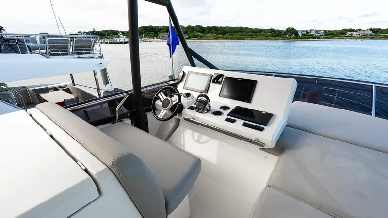 Slide: The Image of Flybridge helm of 2019 Prestige 520 yacht with modern navigation equipment, overlooking serene waters. - 35
