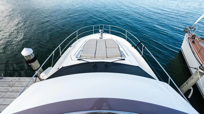 Slide: The Image of 2019 Prestige 520 Flybridge yacht docked, featuring spacious sunbathing area on calm water. - 36