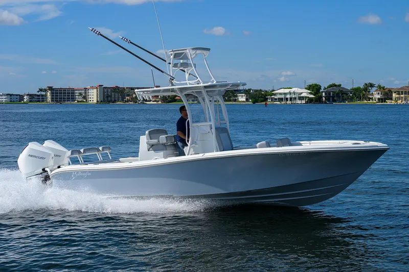 Slide: The Image of 2021 Yellowfin 26 Hybrid boat cruising on a sunny day near coastal buildings. - 4