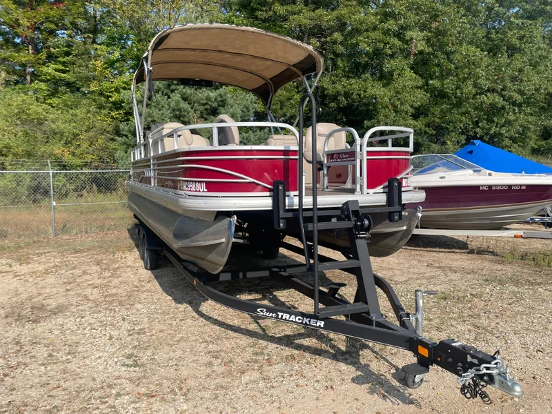 Slide: The Image of 2020 Sun Tracker Fishin' Barge 24 DLX pontoon boat on trailer, parked outdoors. - 4