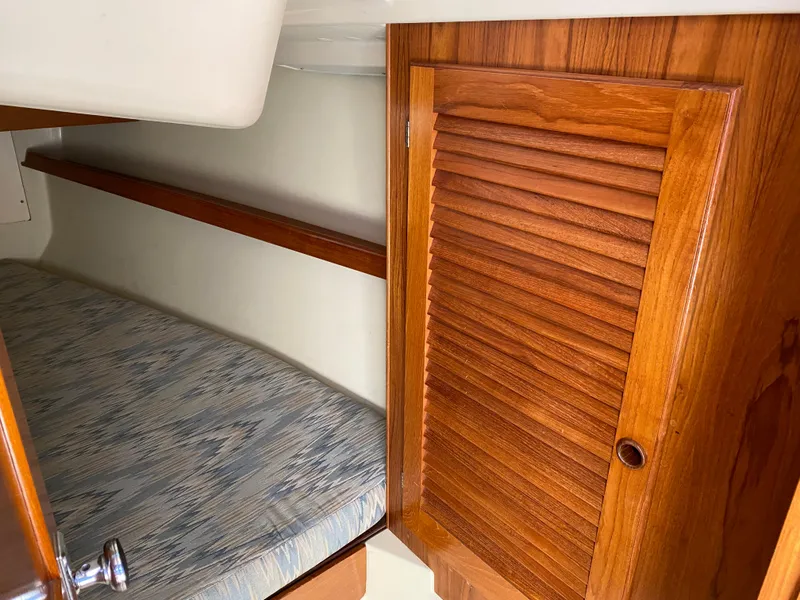 Slide: The Image of 1988 Pearson 28 sailboat interior with wooden cabinet and cushioned berth. - 14
