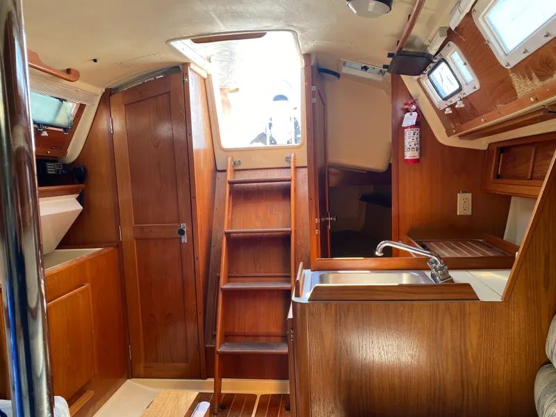 Slide: The Image of Interior of 1988 Pearson 28 sailboat with wooden cabinetry and compact kitchen area. - 15