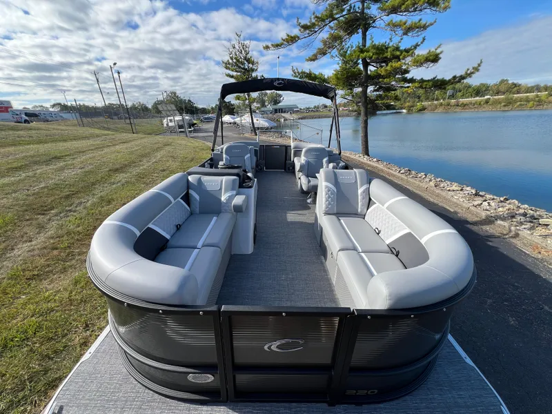 Slide: The Image of 2025 Crest CLASSIC 220 SLC pontoon boat with spacious seating by a serene lake. - 11