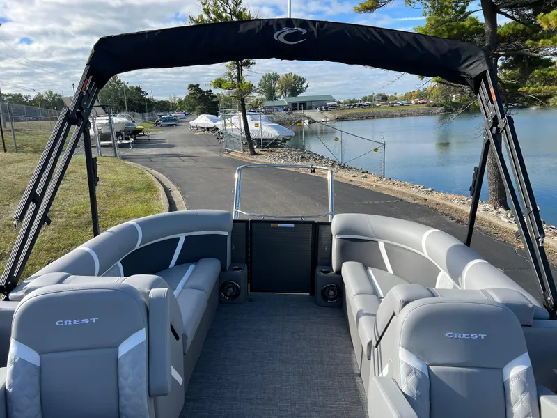 Slide: The Image of 2025 Crest CLASSIC 220 SLC pontoon boat with gray seating, docked by a serene lake. - 17