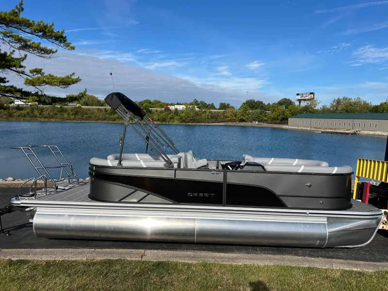 Slide: The Image of 2025 Crest CLASSIC 220 SLC pontoon boat docked by a serene lake. - 3