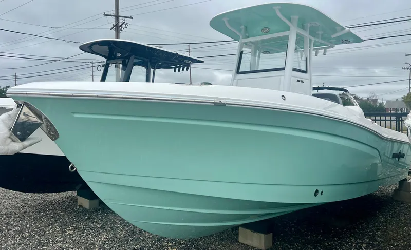The Image of 2025 NauticStar 242OSL boat in mint green, docked on gravel. - 0