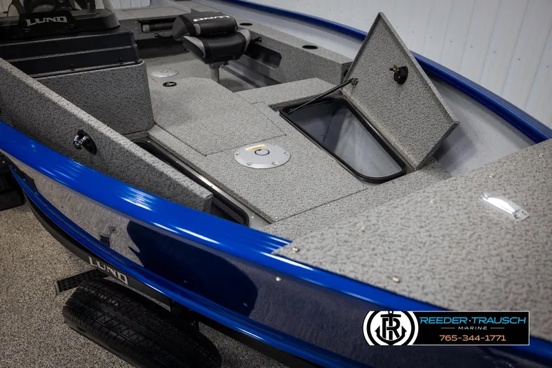 Slide: The Image of 2025 Lund 1775 Adventure SS boat interior with storage compartments, blue exterior, and Reeder-Trausch Marine logo. - 17