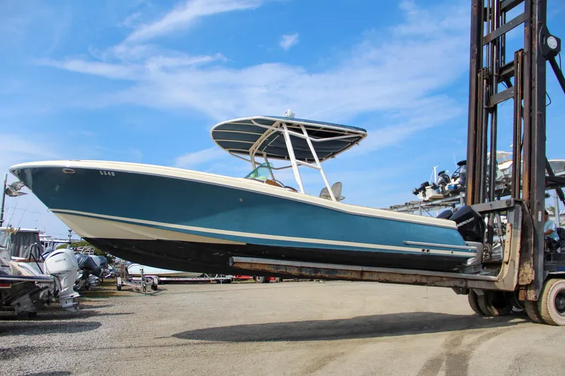 Slide: The Image of 2011 Chris-Craft Catalina 29 Sun Tender on forklift, blue hull, outdoor storage. - 2