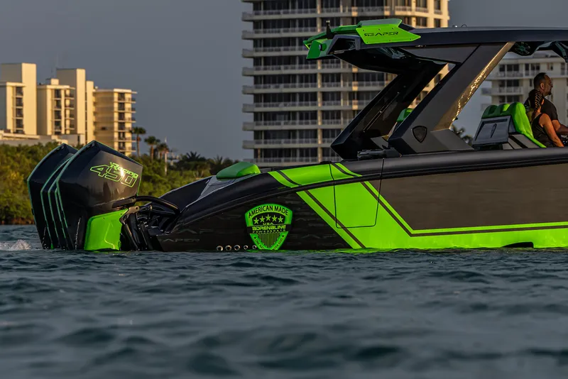 Slide: The Image of 2024 Adrenaline Reaper boat with vibrant green accents on water, cityscape background. - 2