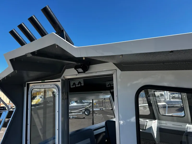 Slide: The Image of 2024 Thunder Jet 26 Alexis Pro XL boat cabin with rod holders, under clear blue sky. - 27