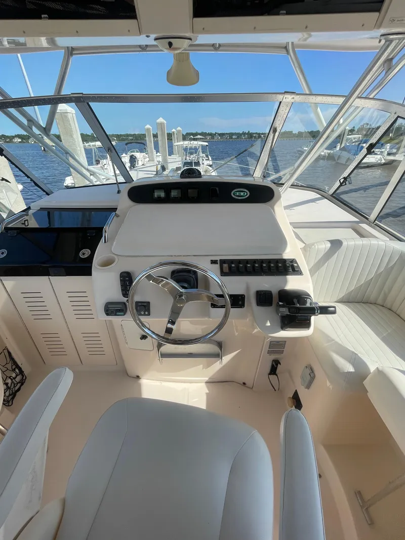 Slide: The Image of 2008 Grady-White Open Express boat helm with steering wheel and controls, docked by the water. - 12