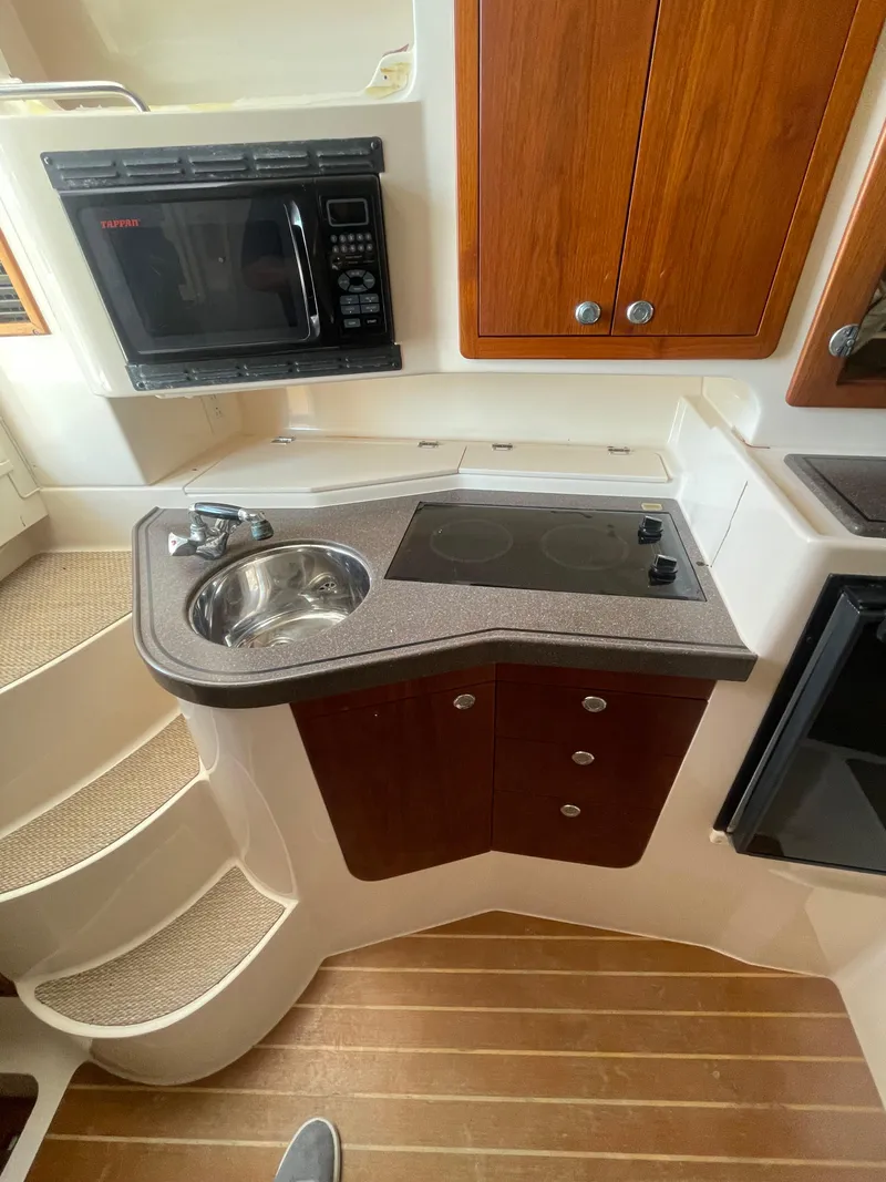 Slide: The Image of 2008 Grady-White Open Express boat kitchen with sink, stove, microwave, and wooden cabinets. - 28
