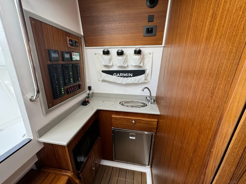 Slide: The Image of Compact galley in 2025 Southport 38 FE boat with wood finish and modern amenities. - 10