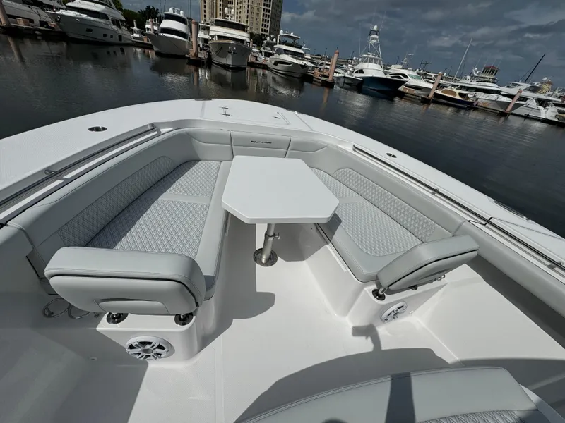 Slide: The Image of 2025 Southport 38 FE boat interior with cushioned seating and table, docked at marina. - 23