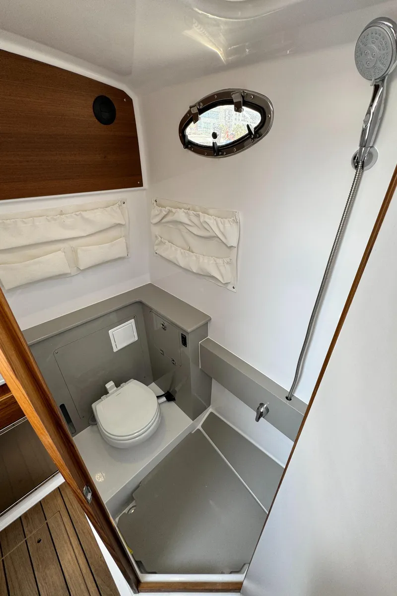 Slide: The Image of 2025 Southport 38 FE boat bathroom with shower, toilet, and porthole window. - 26