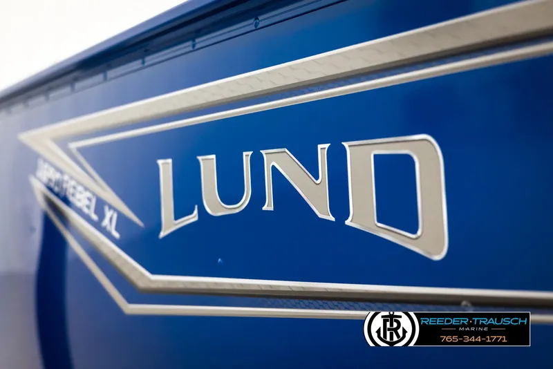 Slide: The Image of 2025 Lund Rebel XL SS boat logo on blue background, Reeder-Trausch Marine branding. - 35